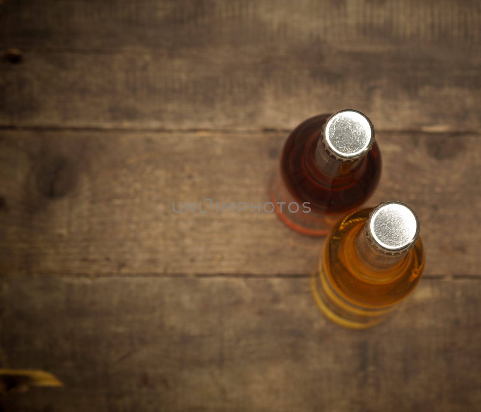 Two bottles of apple juice on an old rustic barn wood background, view from above