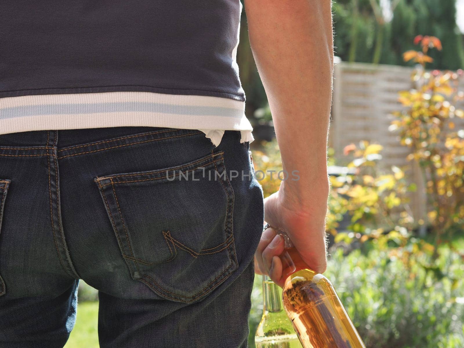 Young man with two bottles of apple juice in the garden, close up shot