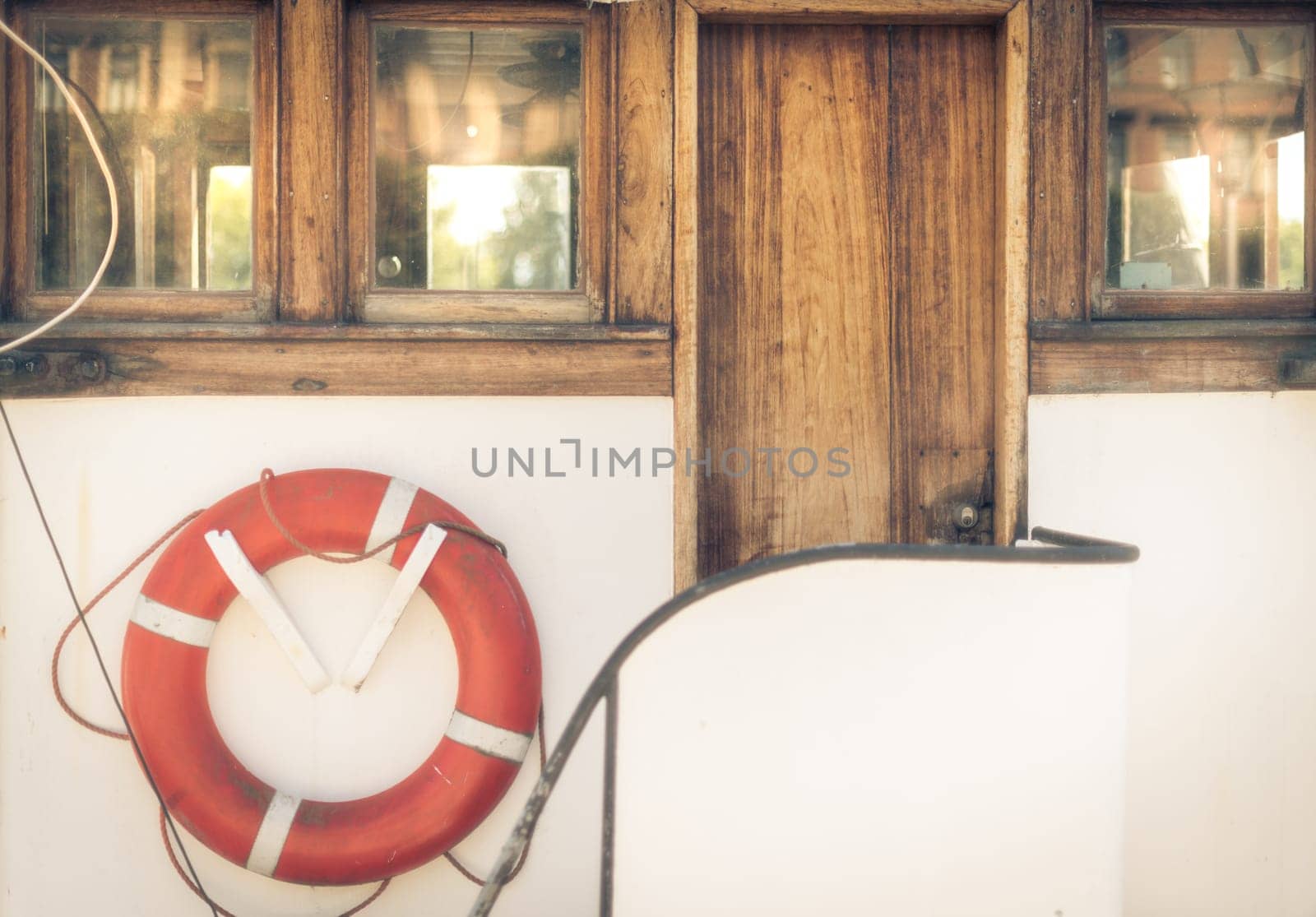 Orange lifebuoy on vintage white boat in port.