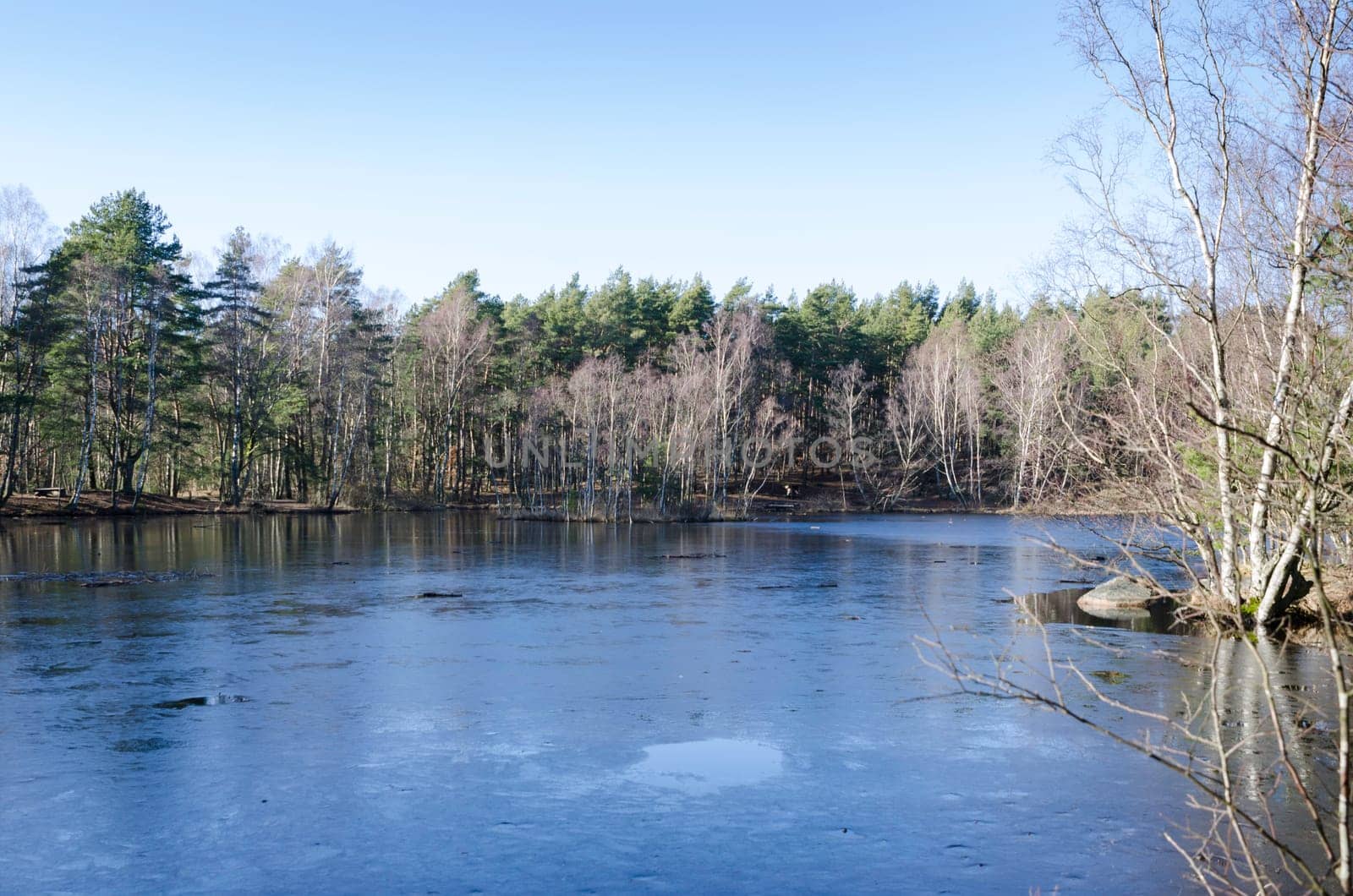 one little lake in Februari the water is still and frozen and the sky is blue