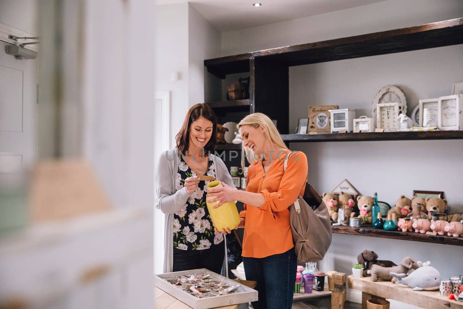 Two women are looking at products in a small shop together.