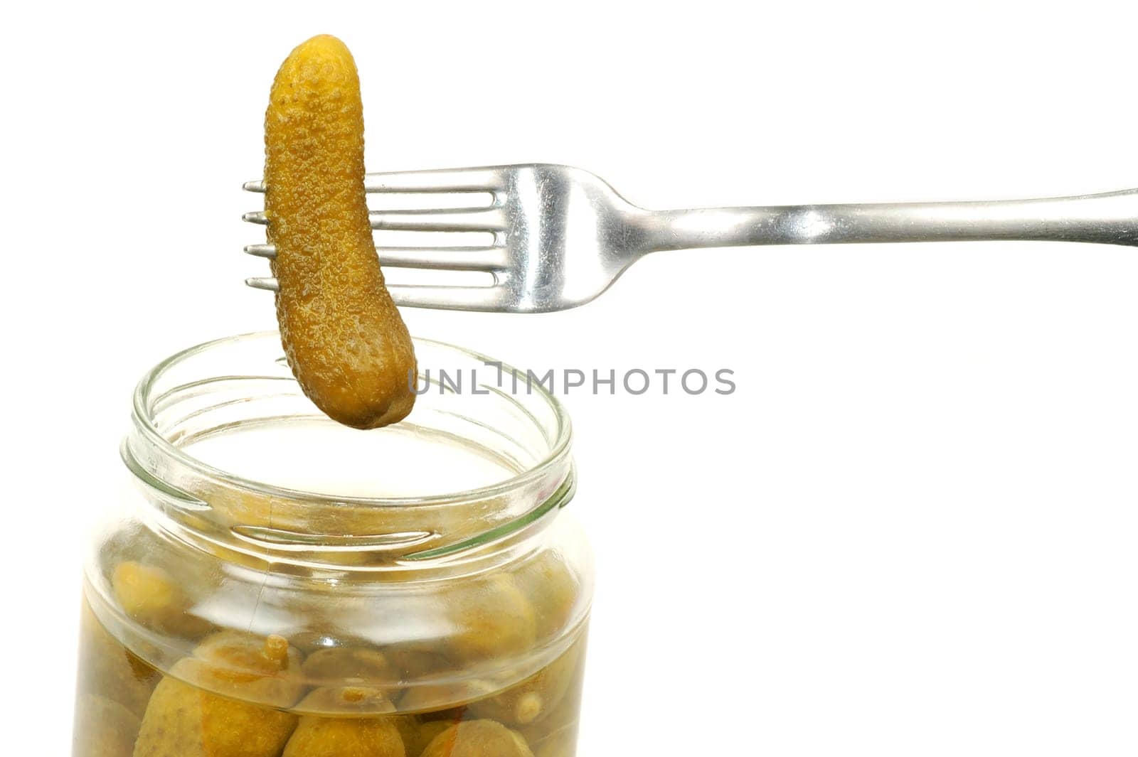 The bottle of pickles and a fork with the cucumber are on white background.