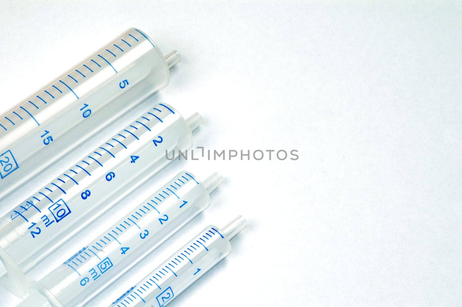 Four syringes in different sizes on white background.