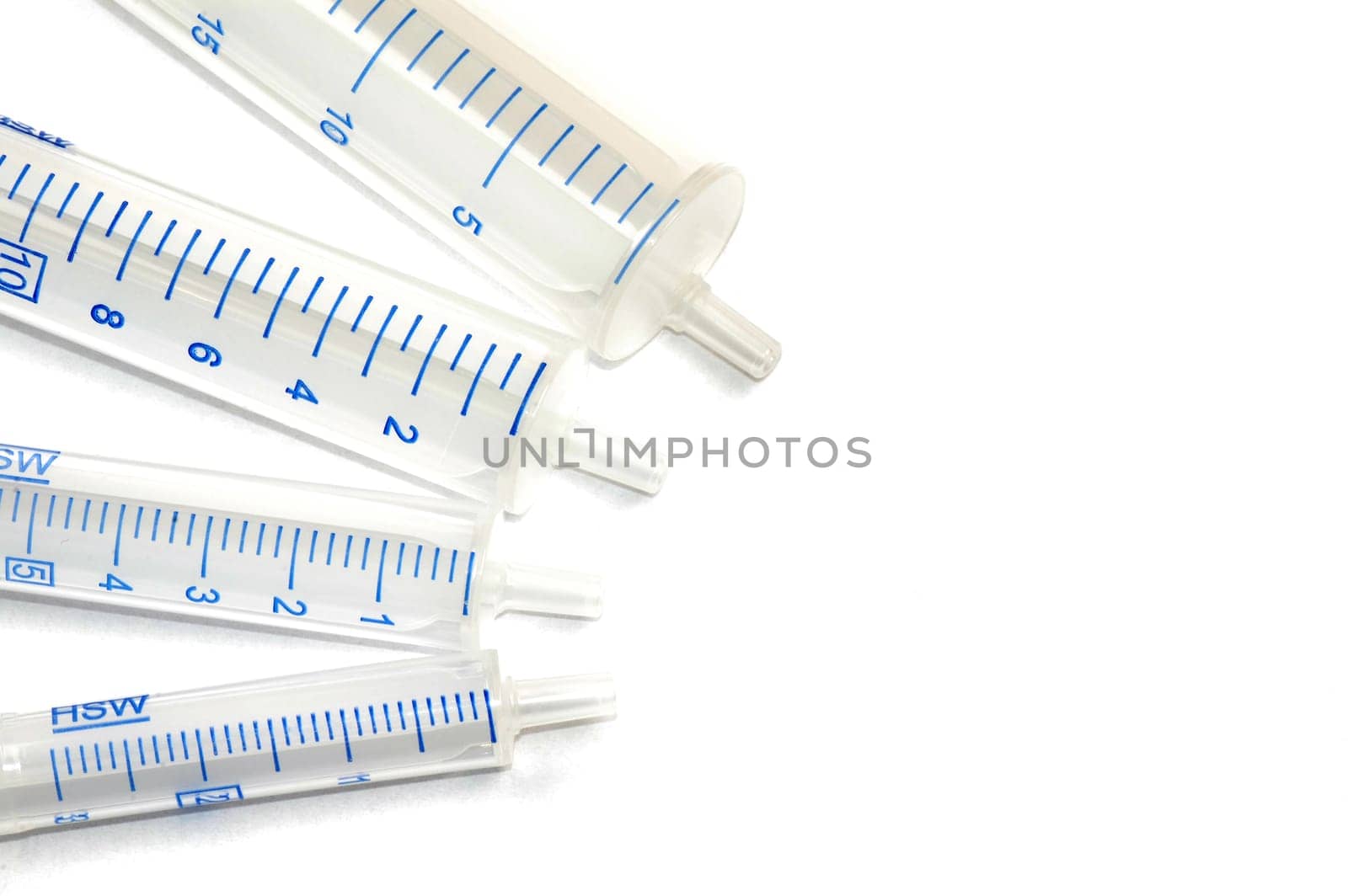 Four syringes in different sizes on white background.