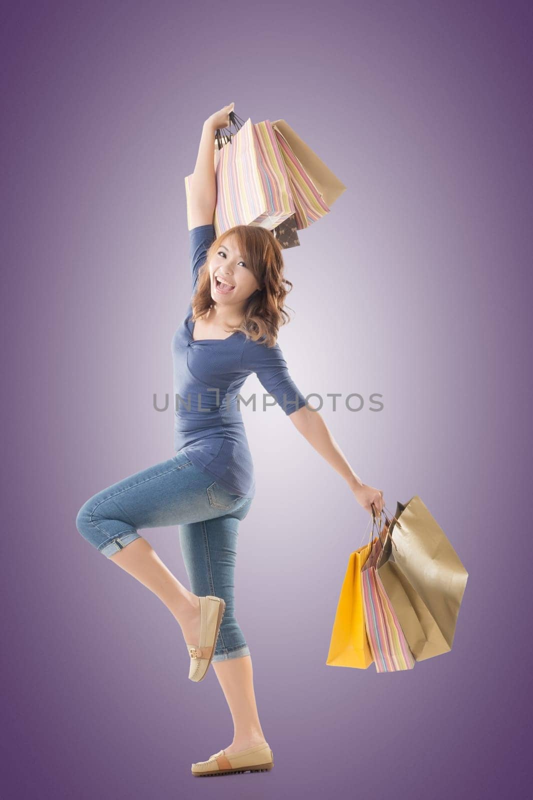 Cheerful shopping woman of Asian holding bags, isolated.