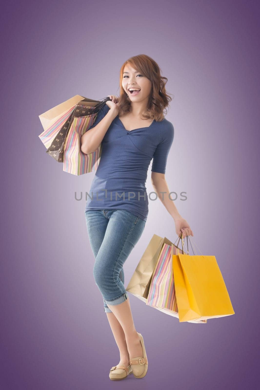 Cheerful shopping woman of Asian holding bags, isolated.