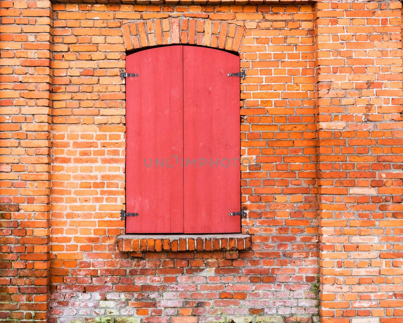 window with red wooden shutters on the brick wall background