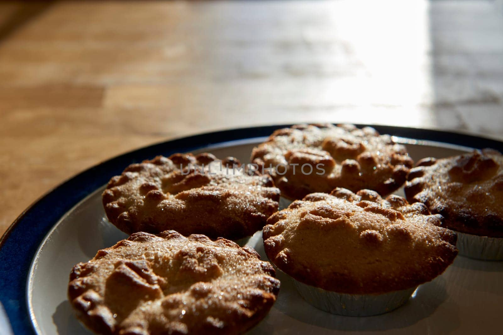 Plate of mince pies shot against the light on a wooden table