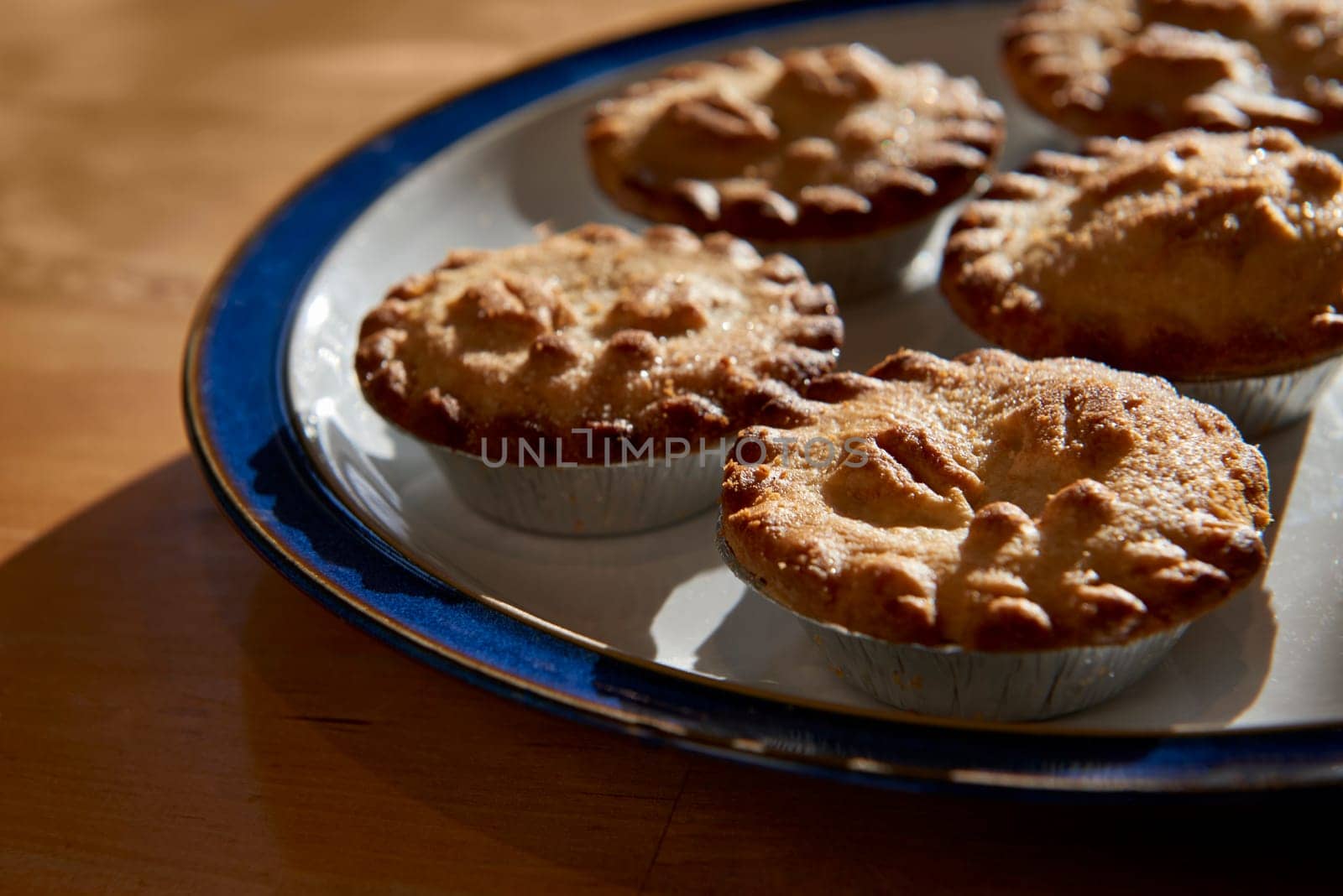 Plate of mince pies shot against the light on a wooden table