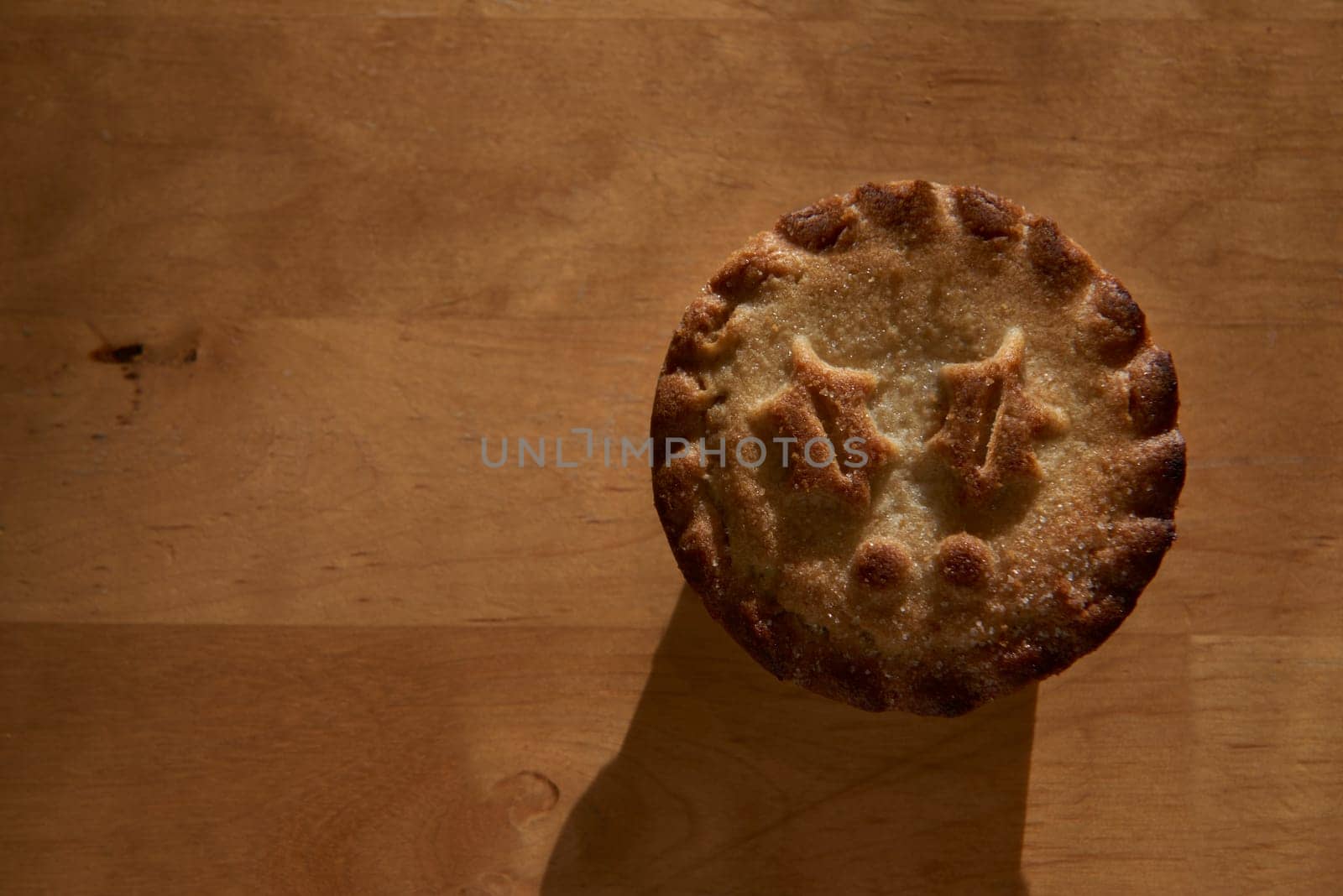 Single mince pie shot directly from above on wooden table, with lots of copy space