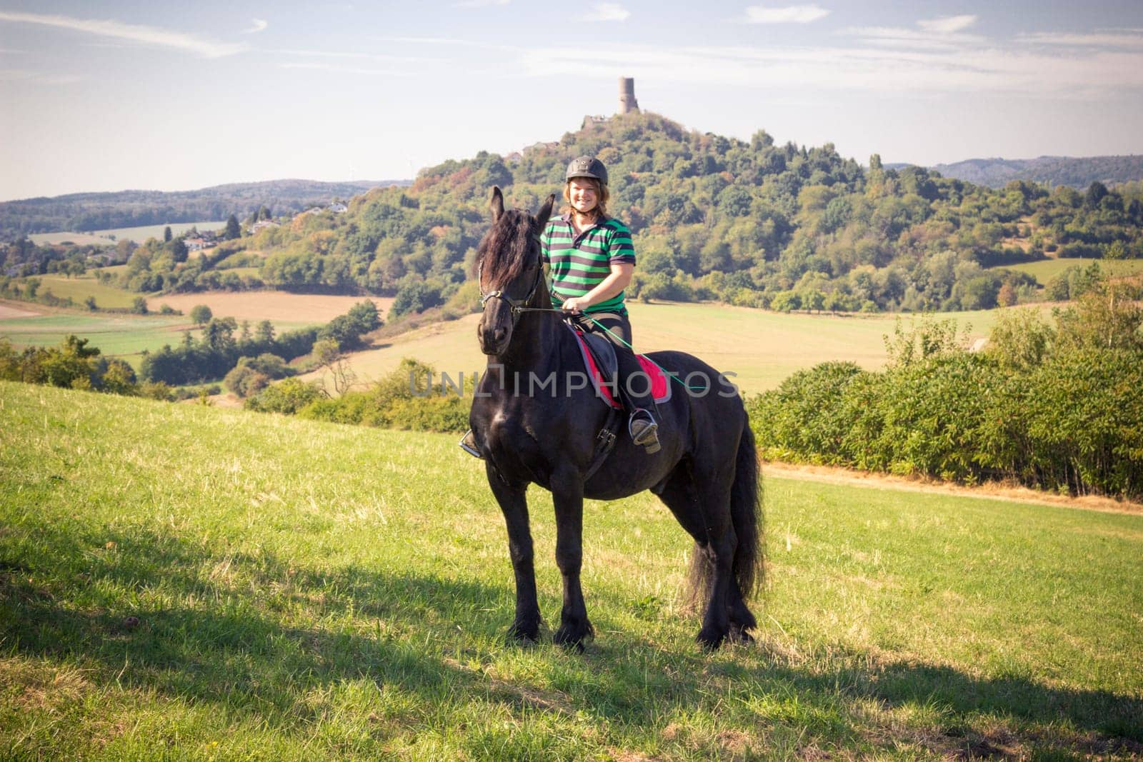 Young rider with her Frisian horse in summer in nature