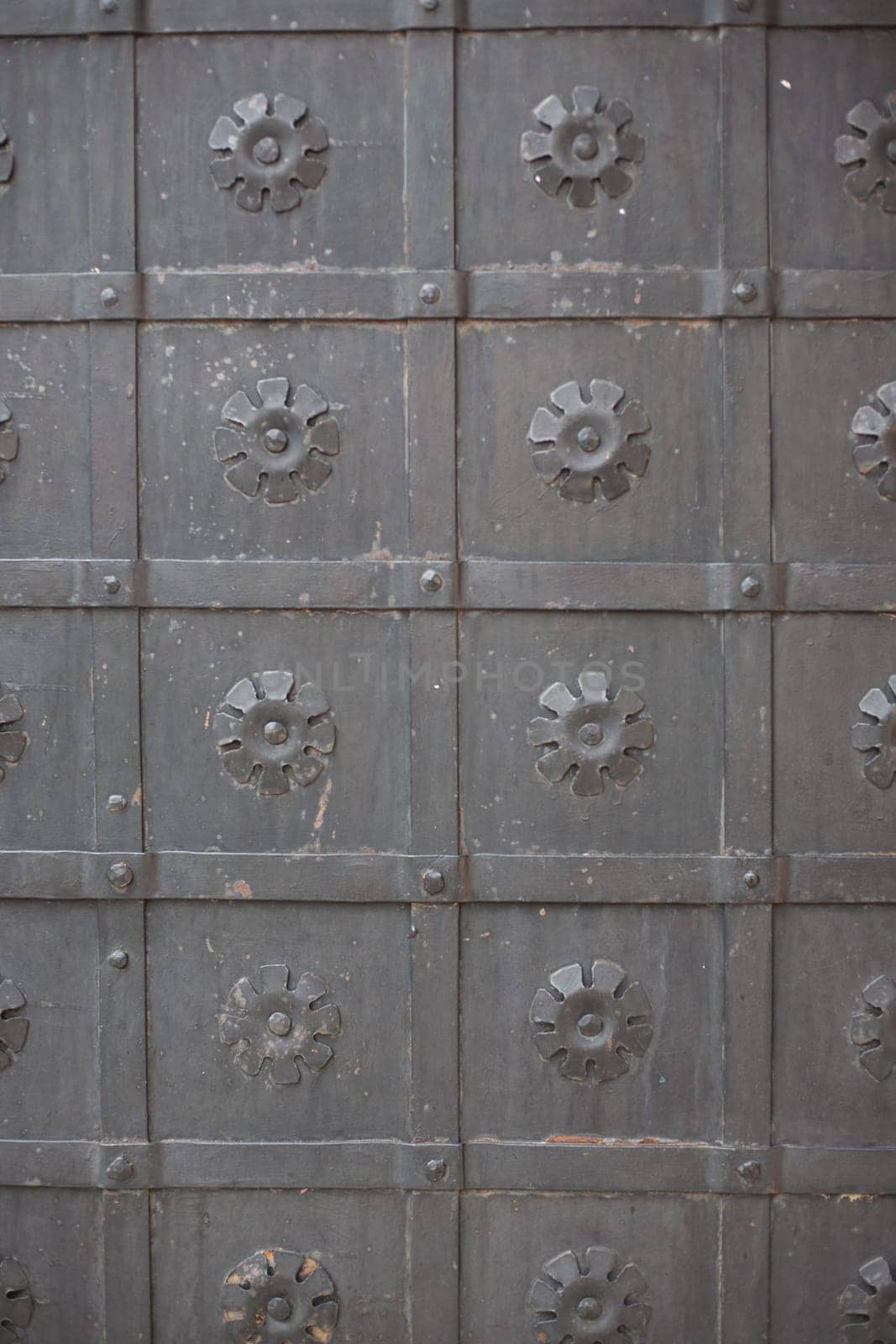 A large massive ancient metal wrought-iron black door with ornamentation