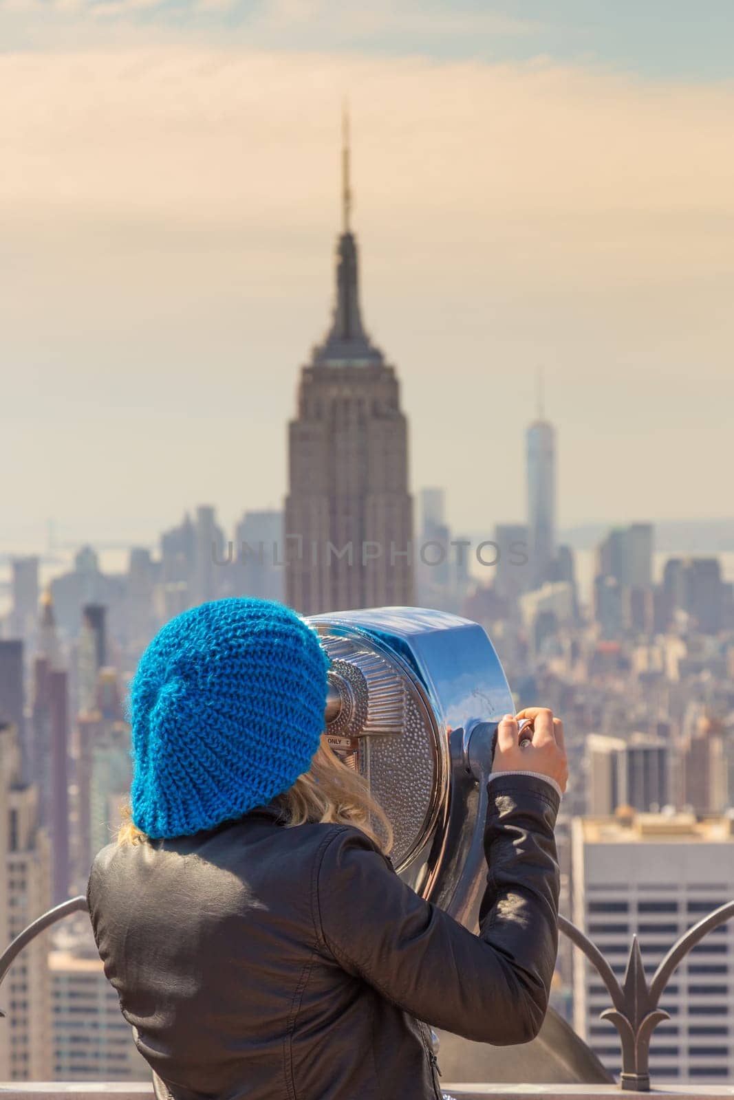 Woman enjoying in New York City panoramic view. Manhattan downtown skyline with illuminated Empire State Building and skyscrapers seen from observation deck terrace.
