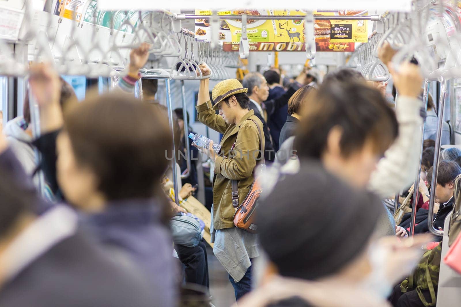 Tokyo, Japan - November 6, 2015: Crowds of daily commuters taking metro ride from work, standing and waiting inside public transport on November 6th in Tokyo, Japan, 2015.