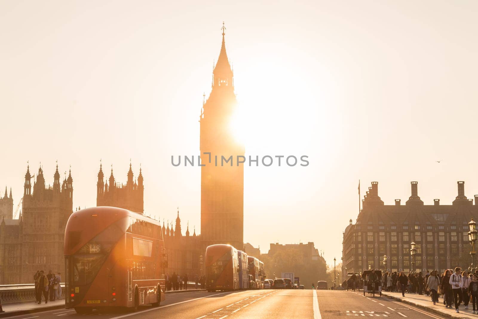 London, UK - April 7, 2015: Traffic and pedestrians passing on Westminster Bridge in sunset on 7th of April, 2017 in London. Big ben and Palace of Westminster aka Houses of Parliament in background.