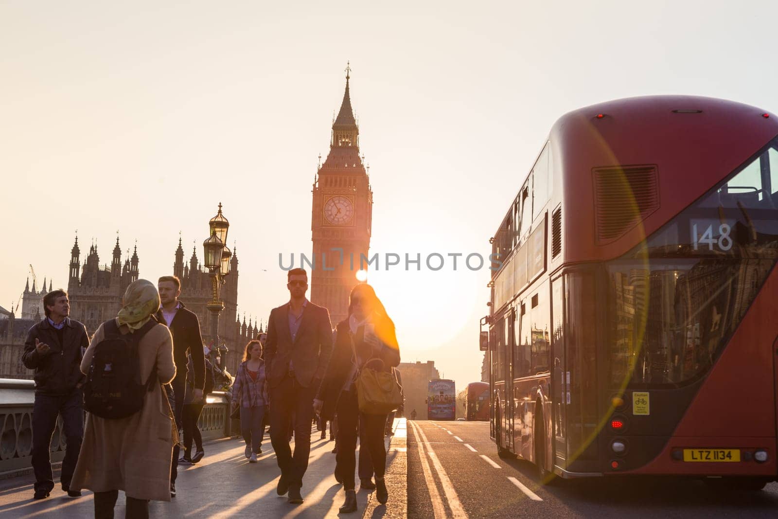London, UK - April 7, 2015: Traffic and pedestrians passing on Westminster Bridge in sunset on 7th of April, 2017 in London. Big ben and Palace of Westminster aka Houses of Parliament in background.