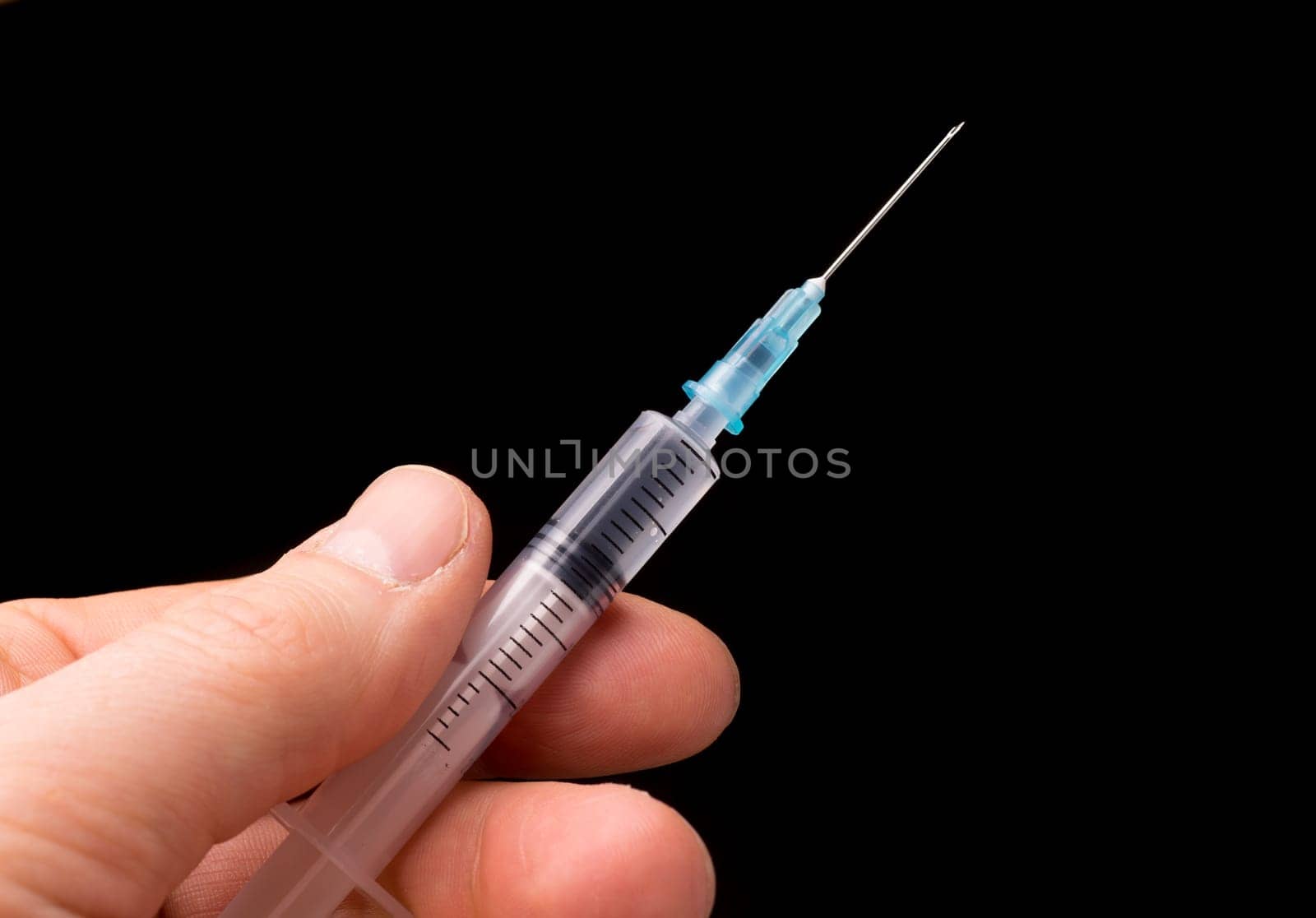 Hand holding a syringe, the syringe is filled with clear liquid and the photo is isolated on black background