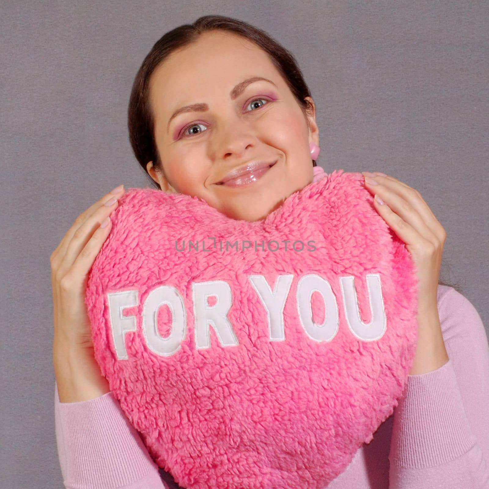 Smiling young woman with pink toy heart with text FOR YOU. Love concept.