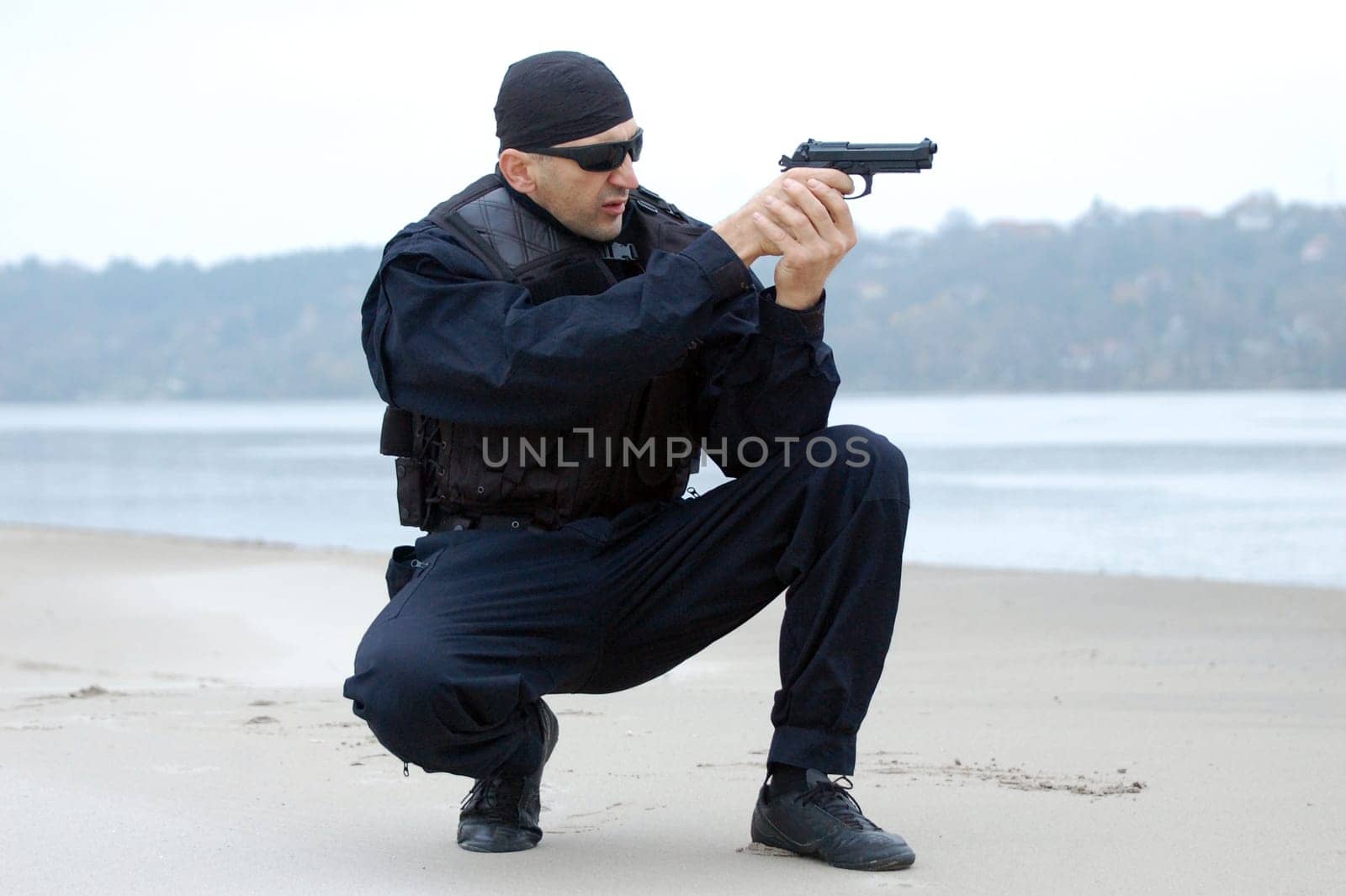 The security man is aiming at something with gun.