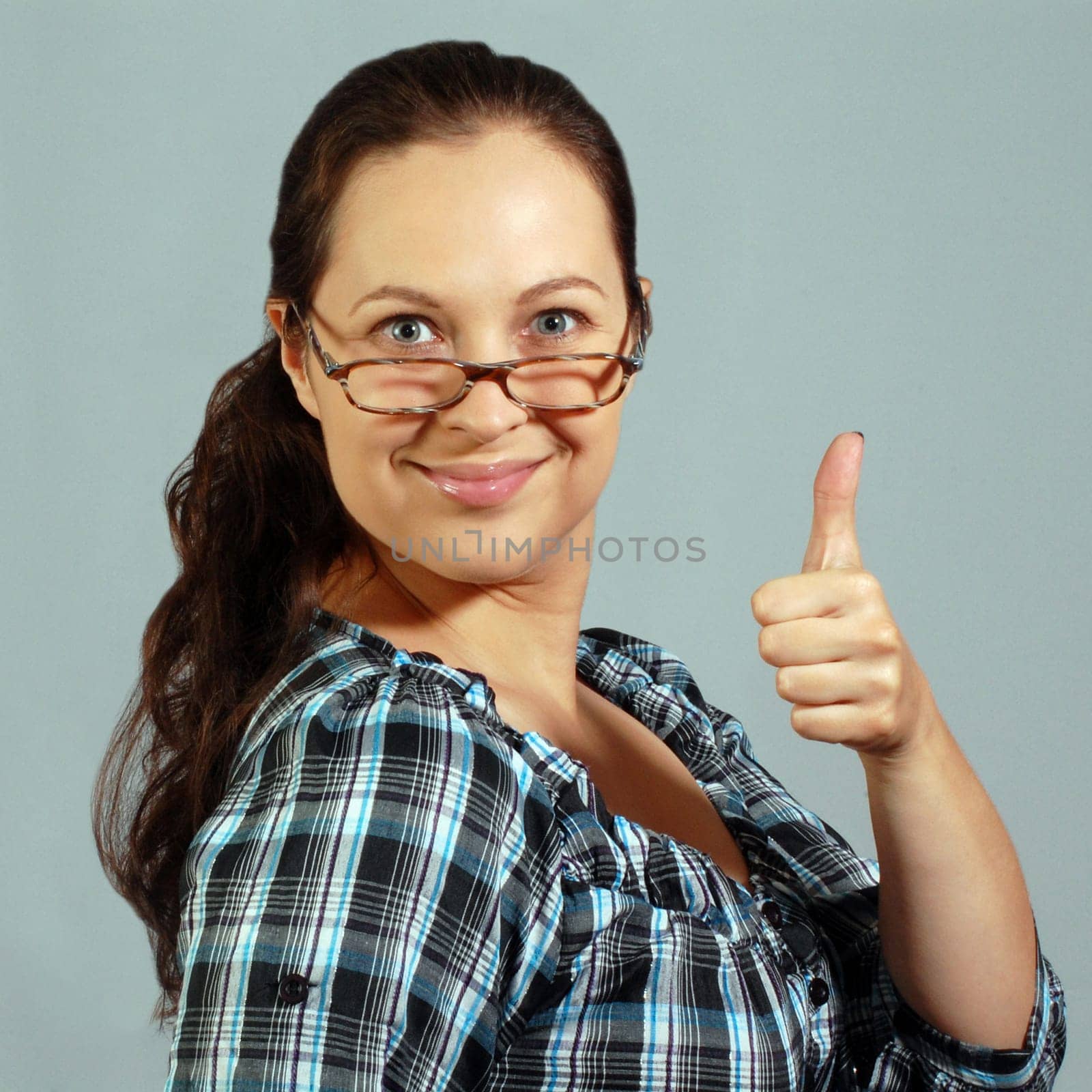 Smiling woman in glasses shows okay sign with finger.