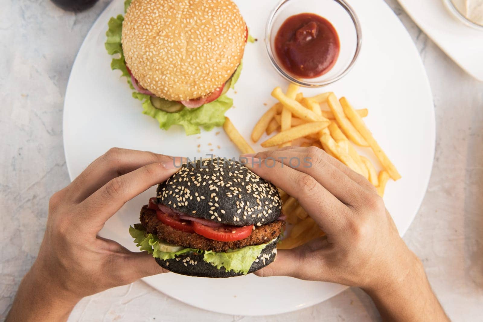 Man eating burgers at table, pov view