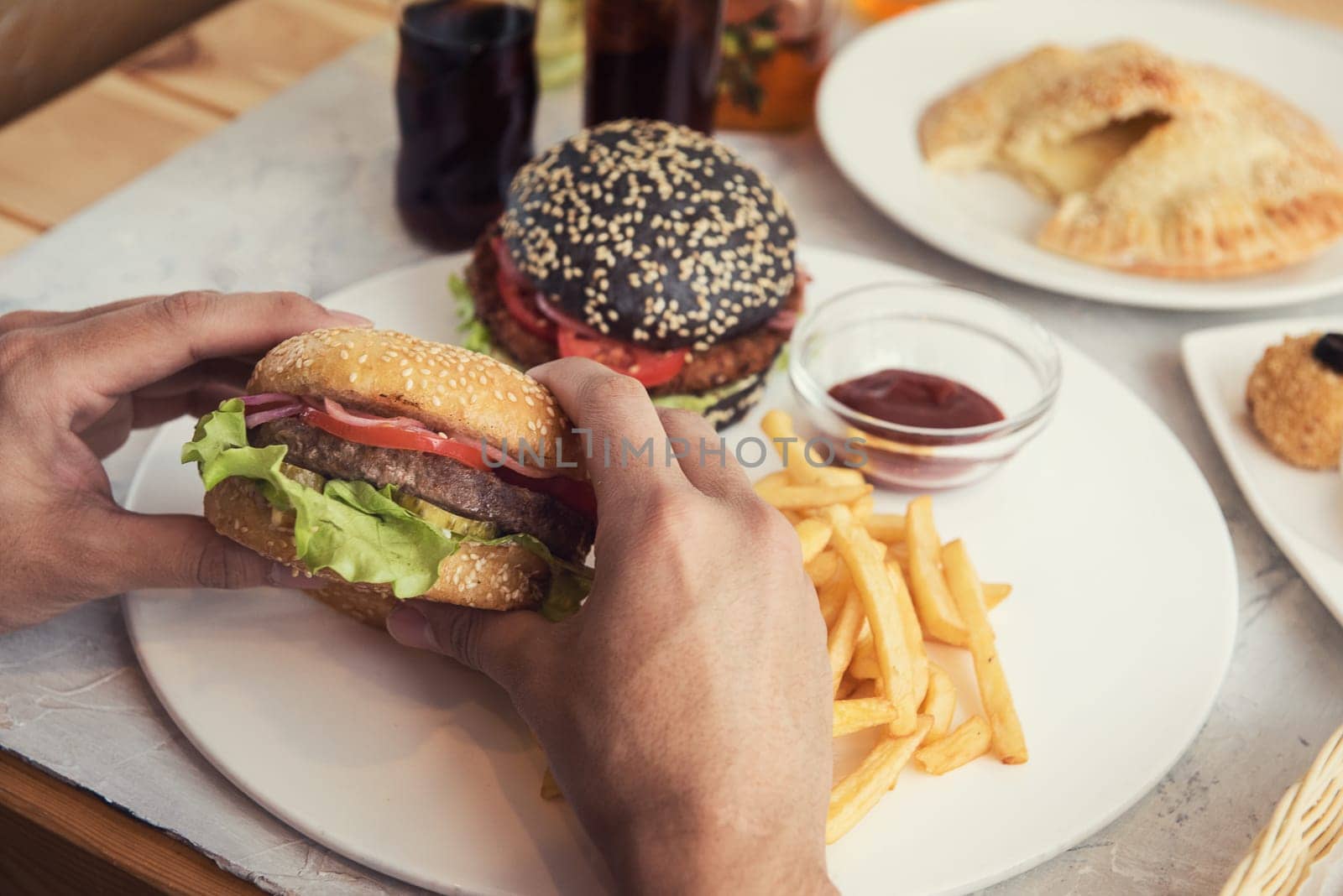 Man eating burgers at table, pov view