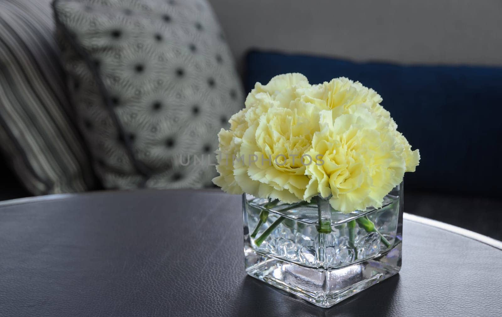 Pink carnation flower in a glass vase on leather table, vintage filtered effect image