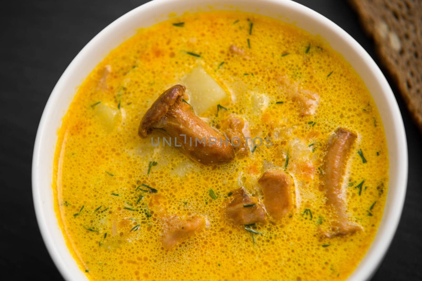 cream soup with mushrooms chanterelles and herbs black stone background,top view