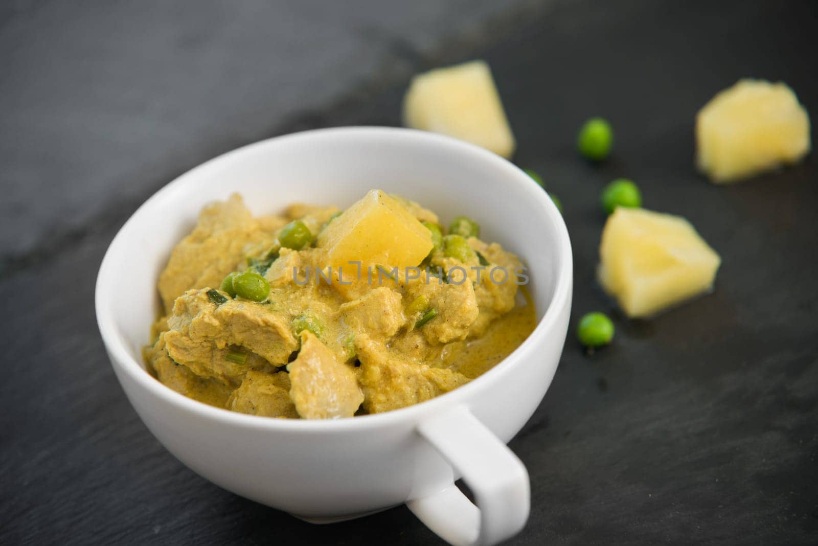 pineapple,pea and pork stew on black stone background