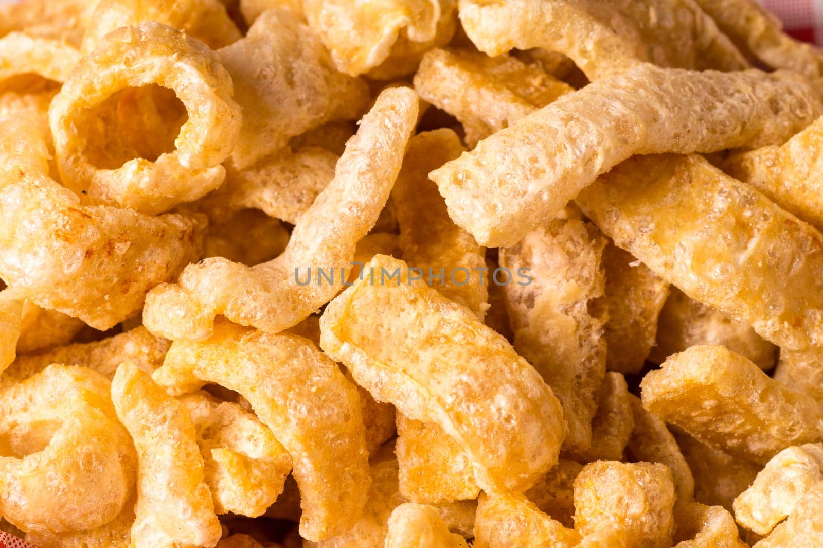 Delicious crispy pork rinds. A crisp salty snack on black glossy background