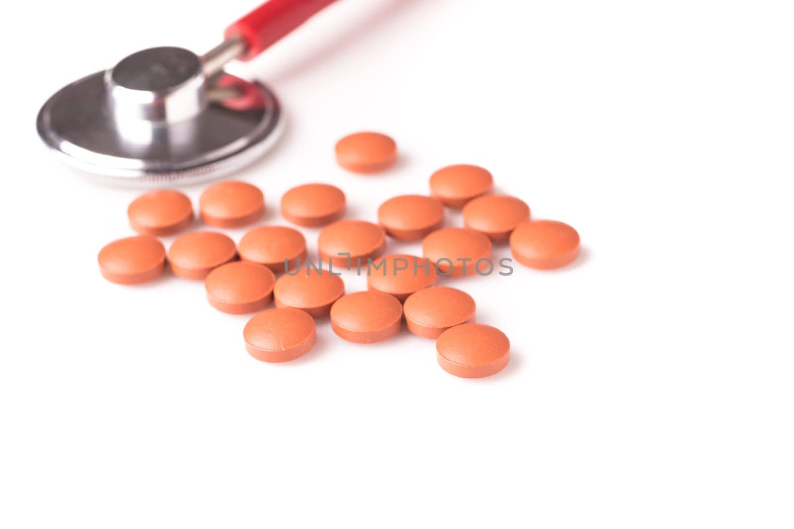 medicine and stethoscope. The stethoscope is next to the pills, isolated on white background