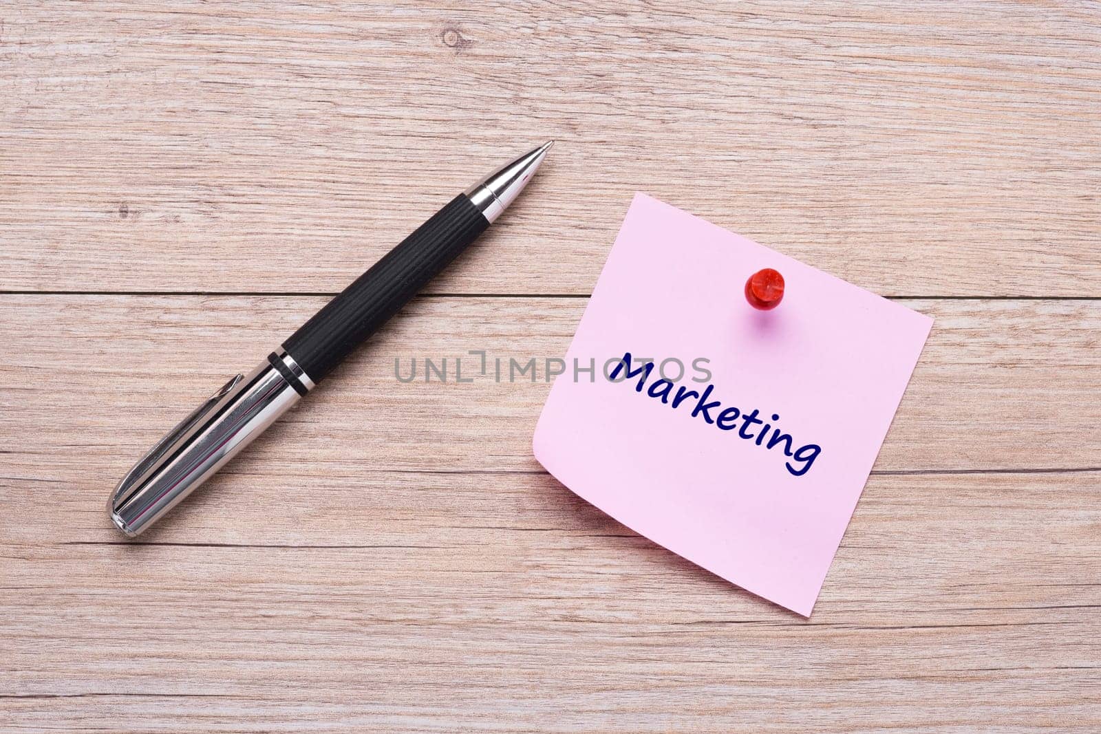 Concept marketing as a word on pink sticky note and ballpoint pen