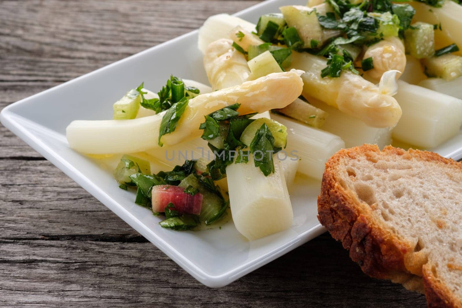 White asparagus as a salad with herbs,rhubarb and slice of bread