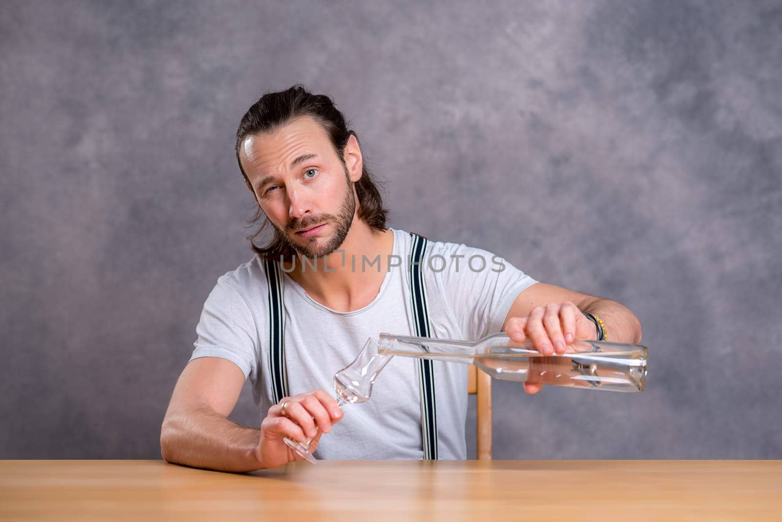 young man in front of gray background drinking clear spirit