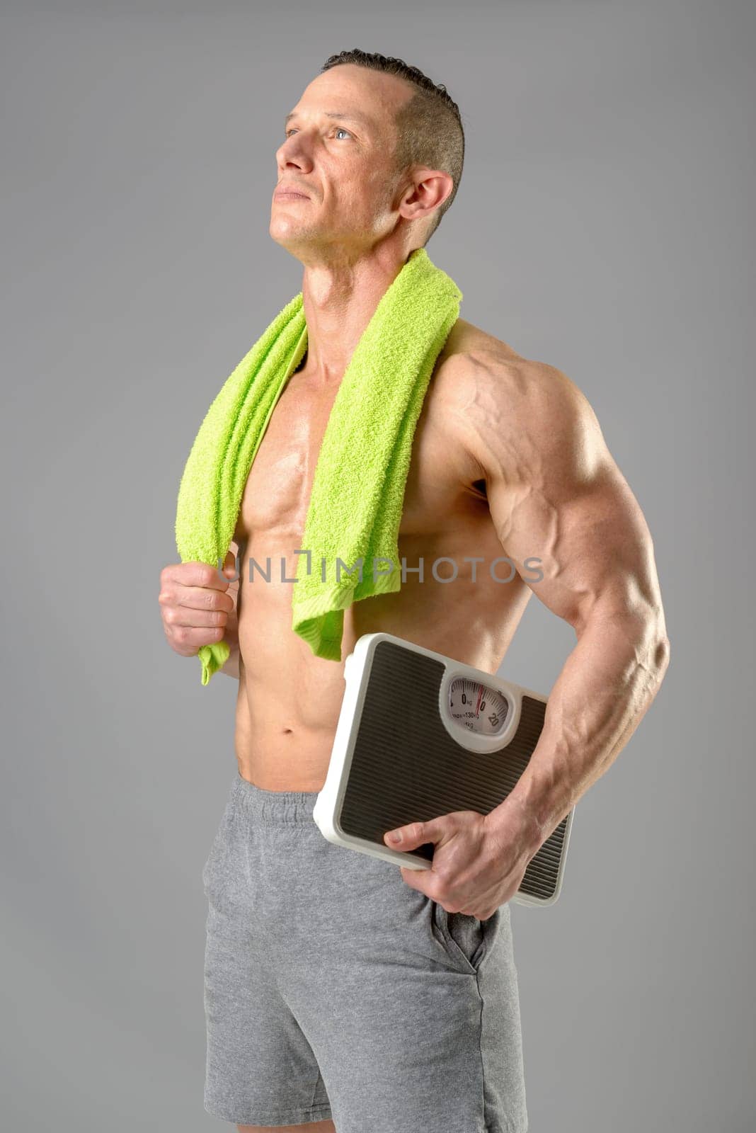 Powerful athletic man with great phisique holding a weight scale.