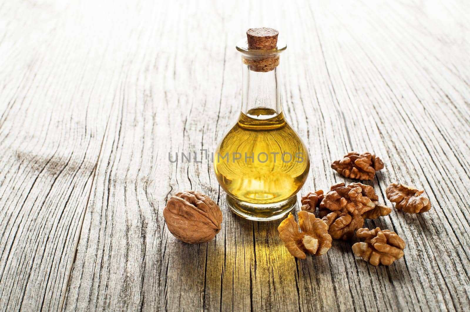Walnut oil in a glass bottle on a wooden background