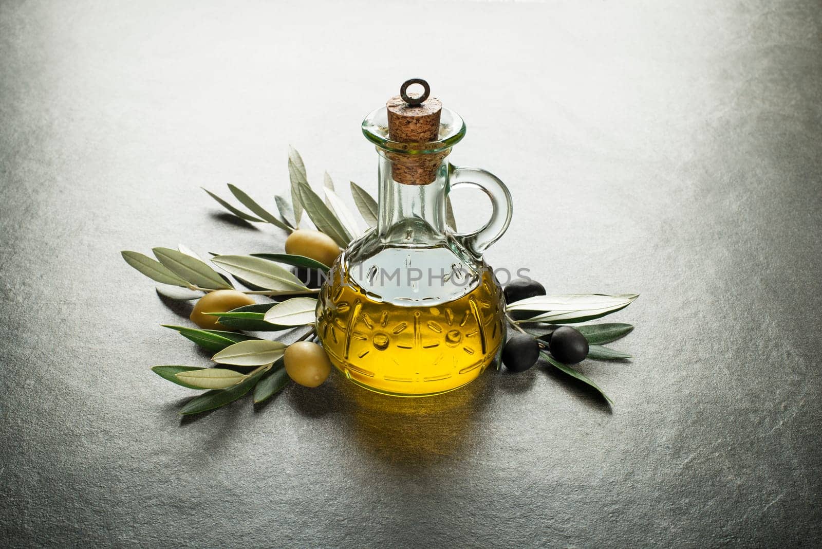 Olive oil and olive branch on the gray table