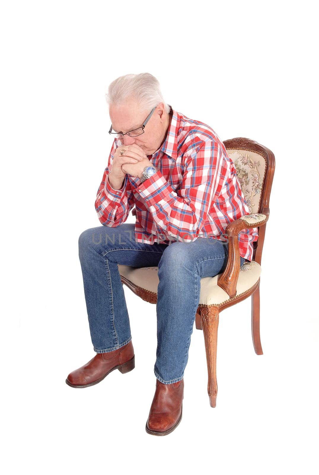 A image of a white hair senior man in a checkered shirt and .glasses sitting in a armchair and thinking, isolated for white background..