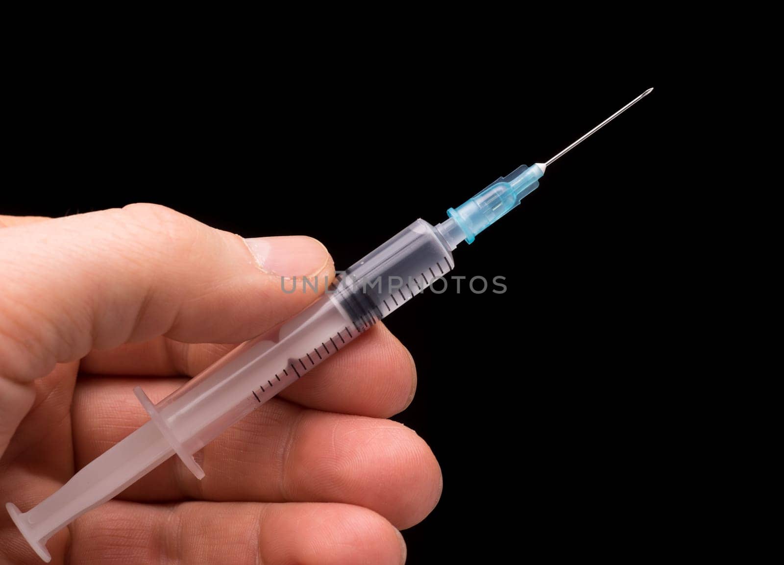 Hand holding a syringe, the syringe is filled with clear liquid and the photo is isolated on black background