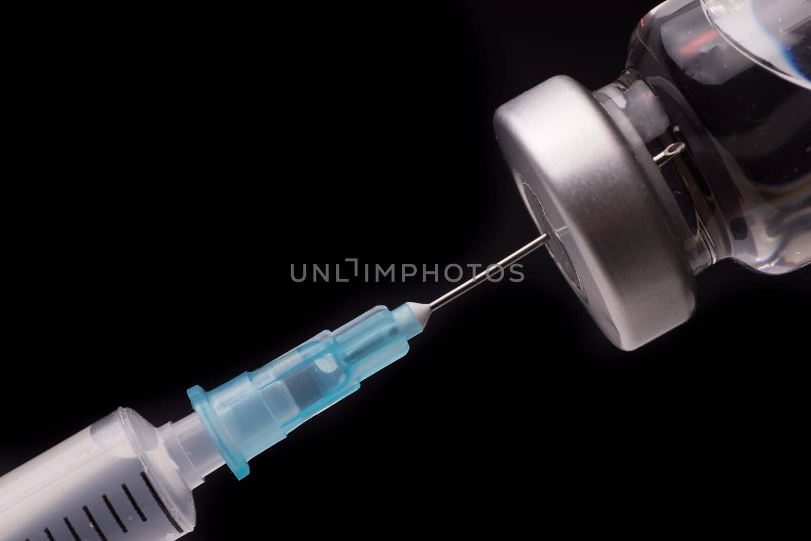 Medical syringe with the needle in the vial. Isolated on black background