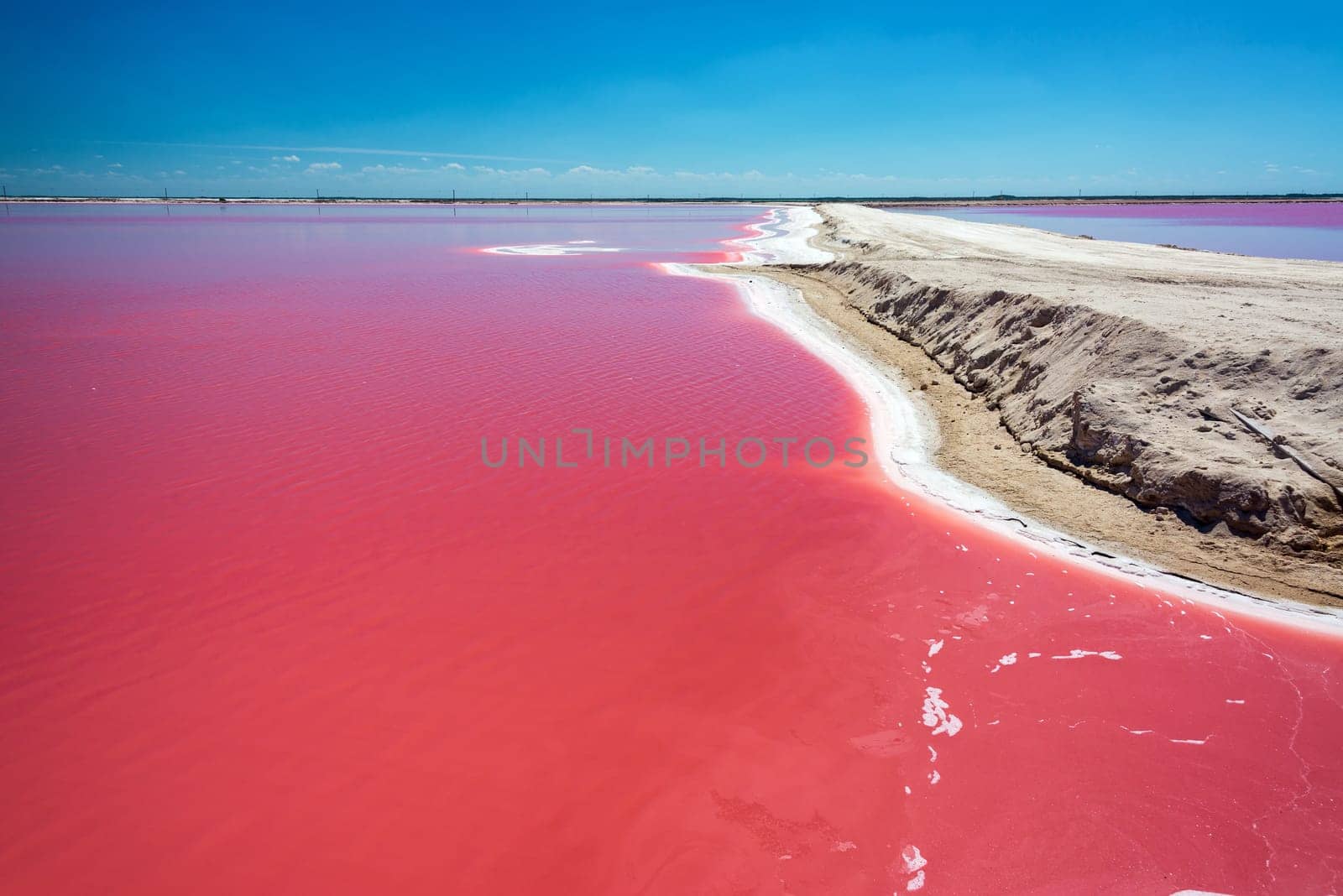 Beautiful red water used in salt production with a dirt road passing by near Rio Lagartos, Mexico