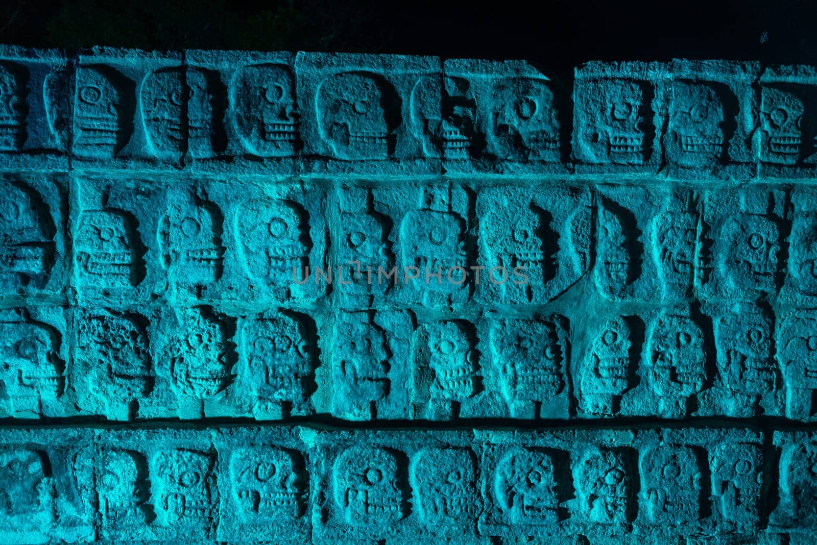 Platform of Skulls known as Tzompantli at night with blue colored light in Chichen Itza, Mexico
