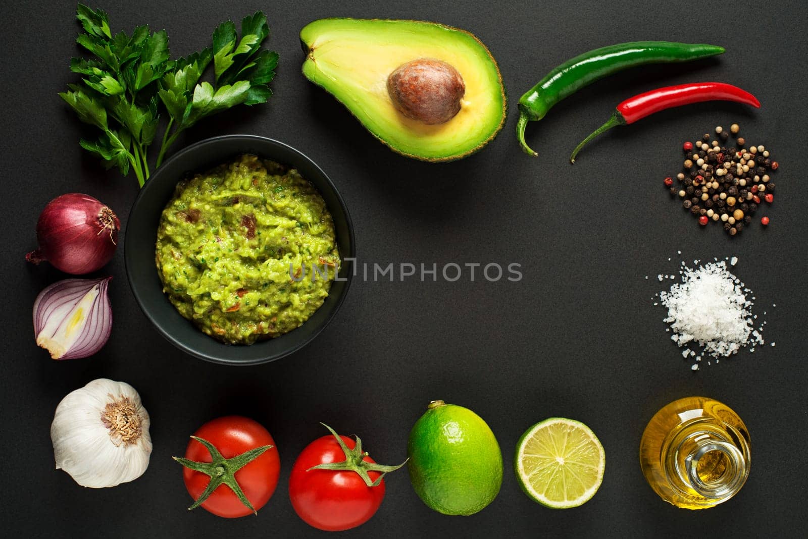 Avocado guacamole with fresh ingredients on black table