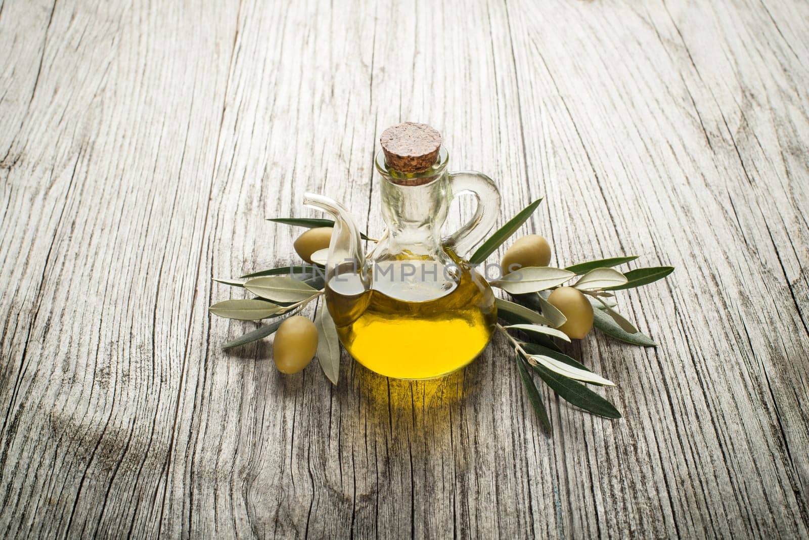Olive oil and olive branch on the wooden table