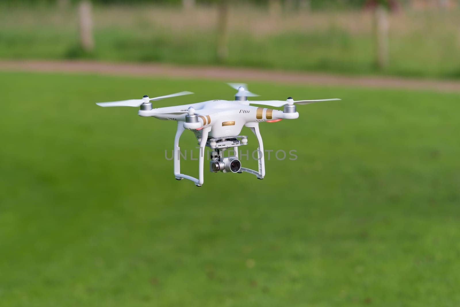 OLDENZAAL, NETHERLANDS - JUNE 19, 2016: DJI Phantom drone with camera attached flying low above the grass