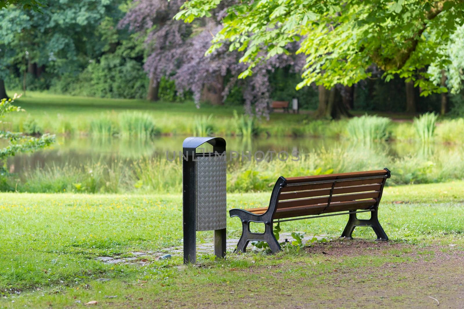 bench with dust bin next to it in a park