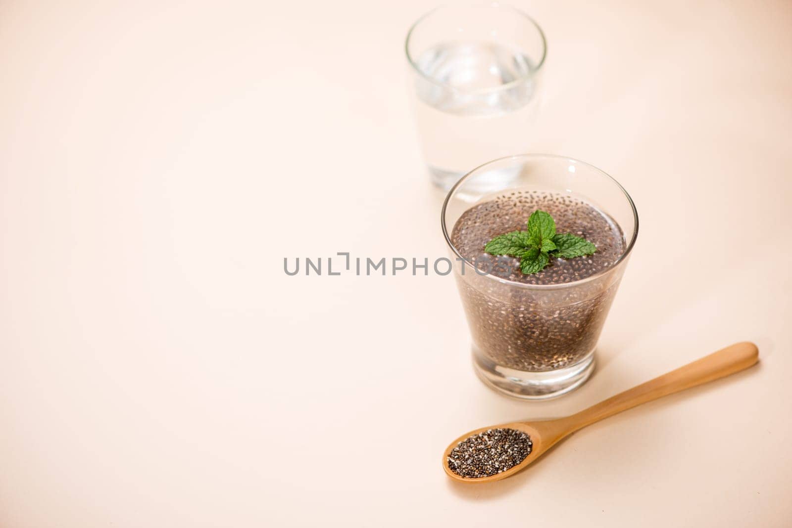Glass of water with cup of healthy chia seeds and spoon. Text space.
