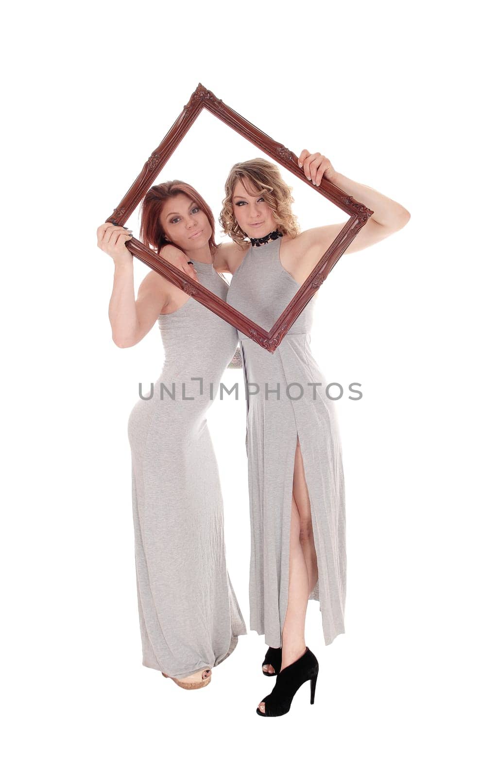 A beautiful young slim woman in gray dress's looking trough a picture.frame in full length, isolated for white background..