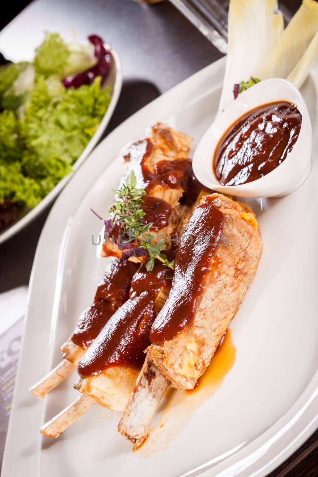 Grilled pork ribs Spareribs with barbecue sauce marinade and herb salad on a plate