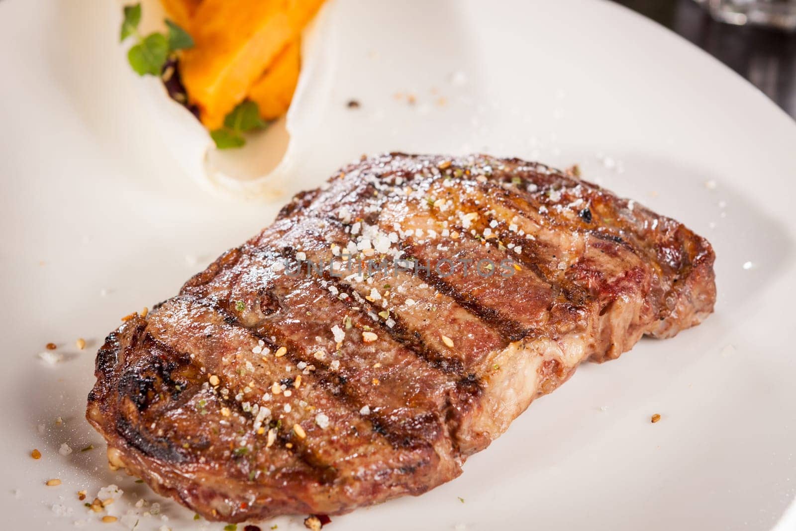 Succulent grilled beef fillet steak with homemade herb butter on a plate isolated against a white background